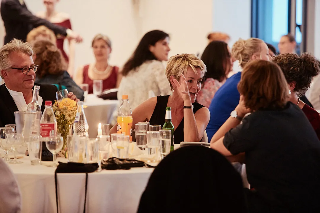 Guests around a candle-lit banquet table in the pause between courses.