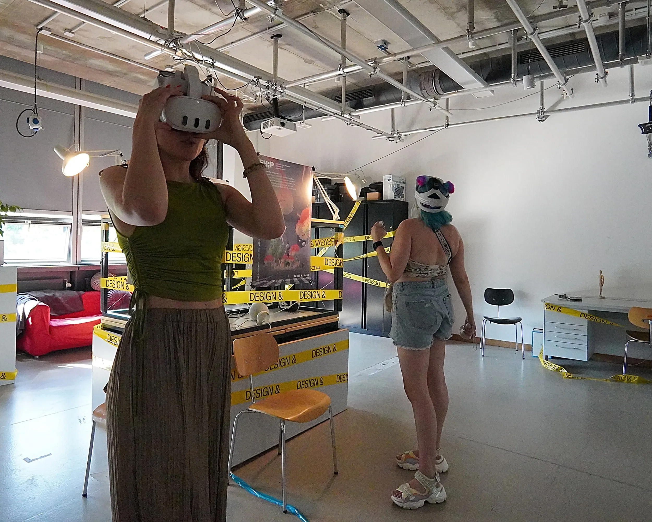 Two visitors in VR headsets exploring a taped-off area at an exhibition.