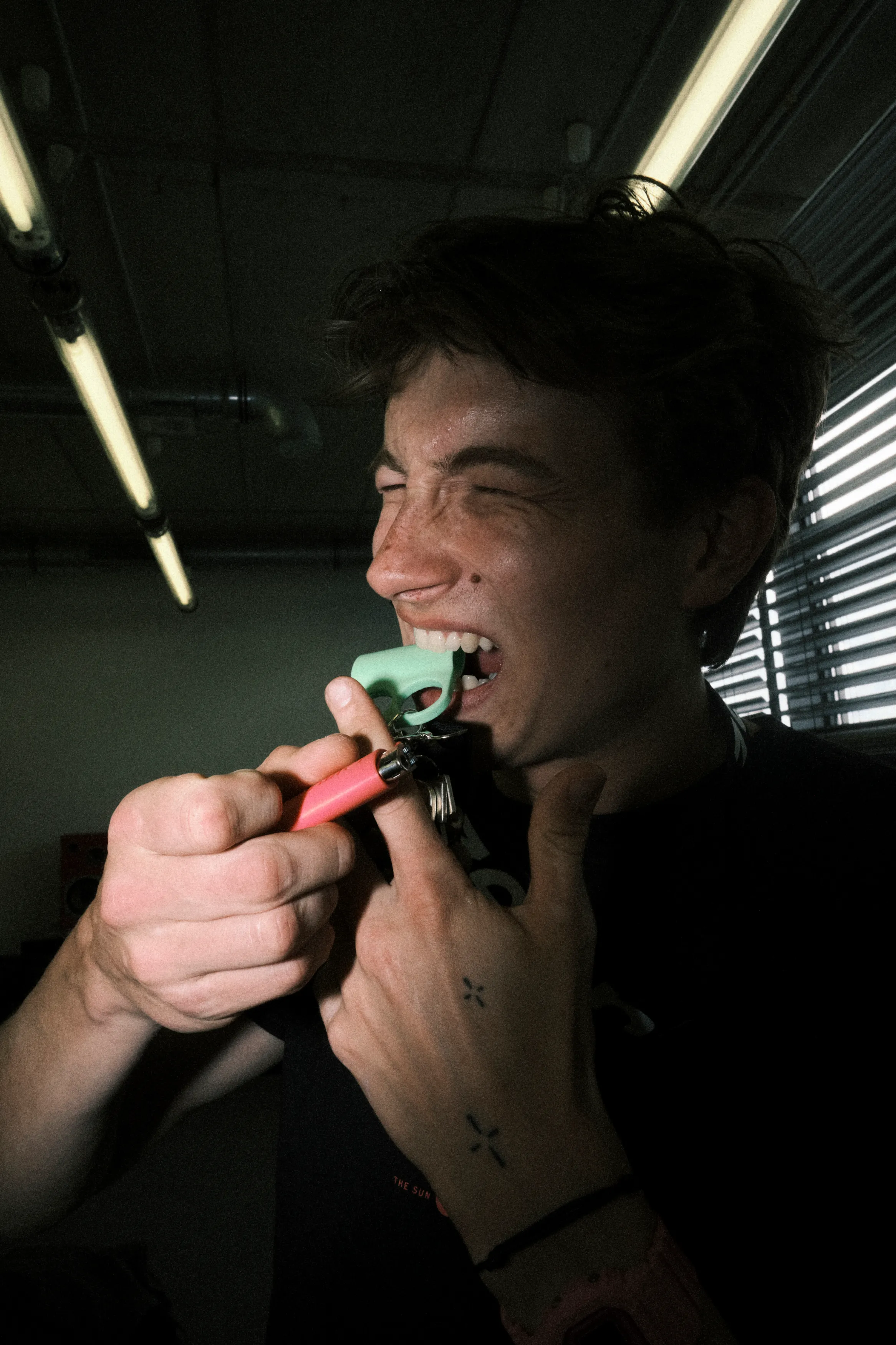 A person lighting up in a dimly lit room, face half in shadow.